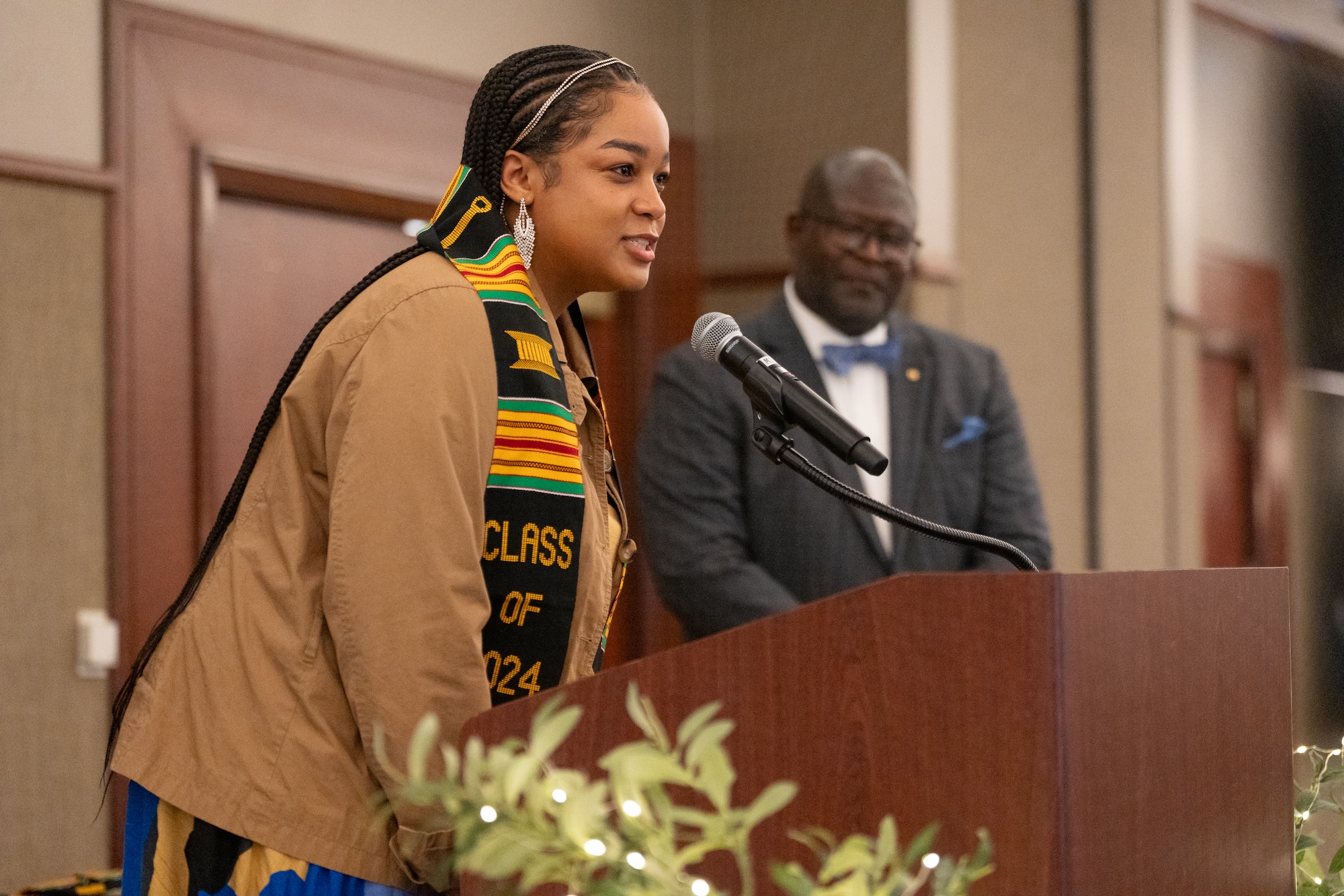 Student giving remarks at CASE Salute to Excellence in Spring 2024. Director Andre Thorn stands in background